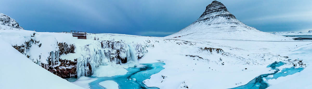 A large panorama of the famous kirkjufell mountain with the kirkjufellfoss on iceland on a cloudy day 