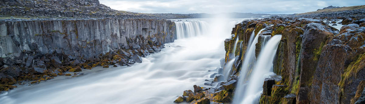Long exposure of Selfoss waterfall in Iceland on a cloudy, rainy day  Wild river runs between steep basalt cliffs  Icelandic volcanic landscape 