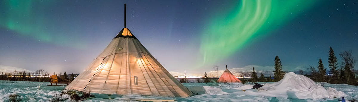 Northern Lights dance above a traditional Saami tent, called lavvu, near Tromsø, Norway 