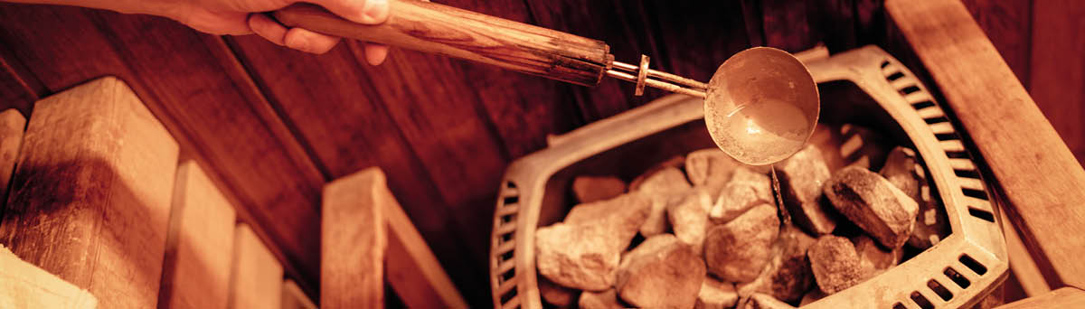 Close-up of a unrecognizable man watered hot stones in the finnish sauna 
