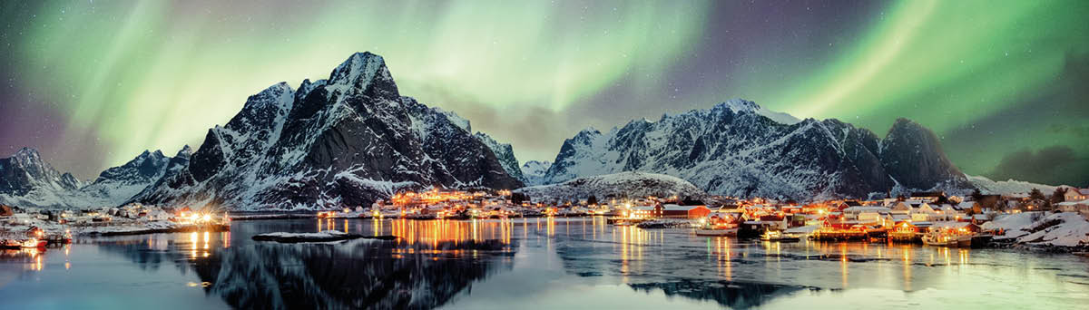 Aurora borealis dancing on mountain in fishing village at Reine, Lofoten, Norway