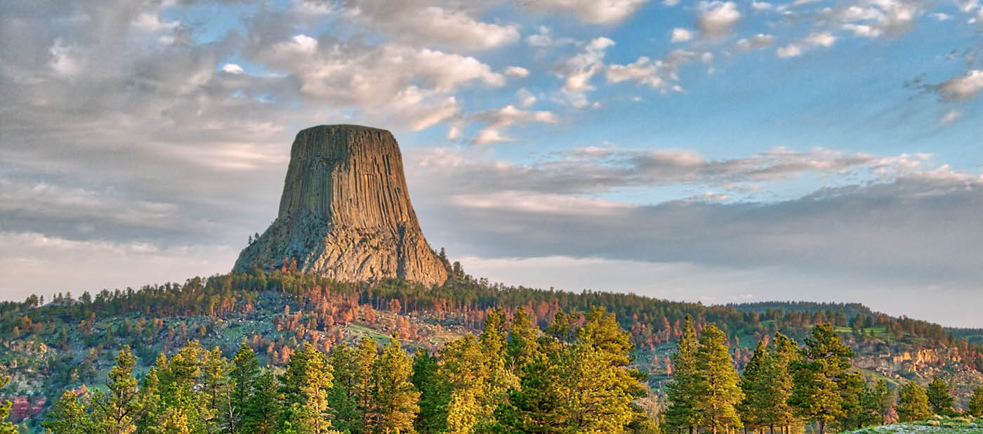 Devil's Tower National Monument in Wyoming Under the Early Morning Cloudy Sky with the forest in the foreground