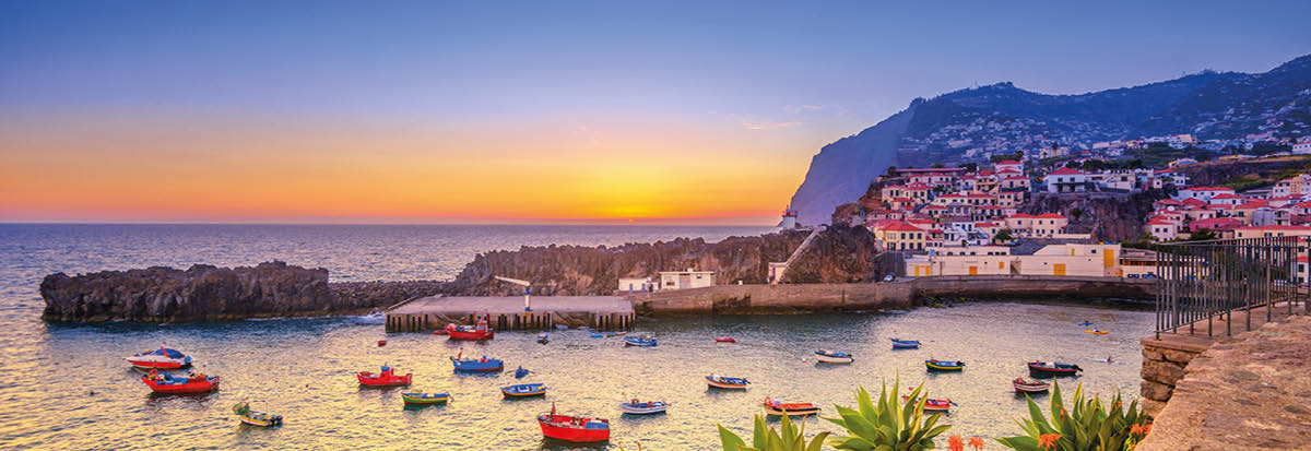 The beautiful fishing village of Camara de Lobos on the portugese Island of Madeira at sunset; in the back the landmark Cabo Girao, the world second highest steep cliff (580 m) 