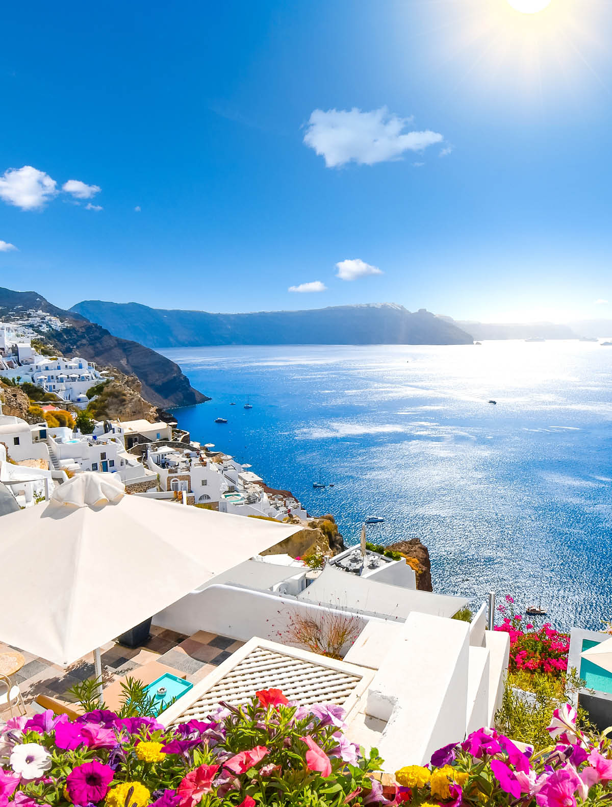 View from an open window with blue shutters of the Aegean sea, caldera, coastline and whitewashed town of Oia, Santorini, Greece.