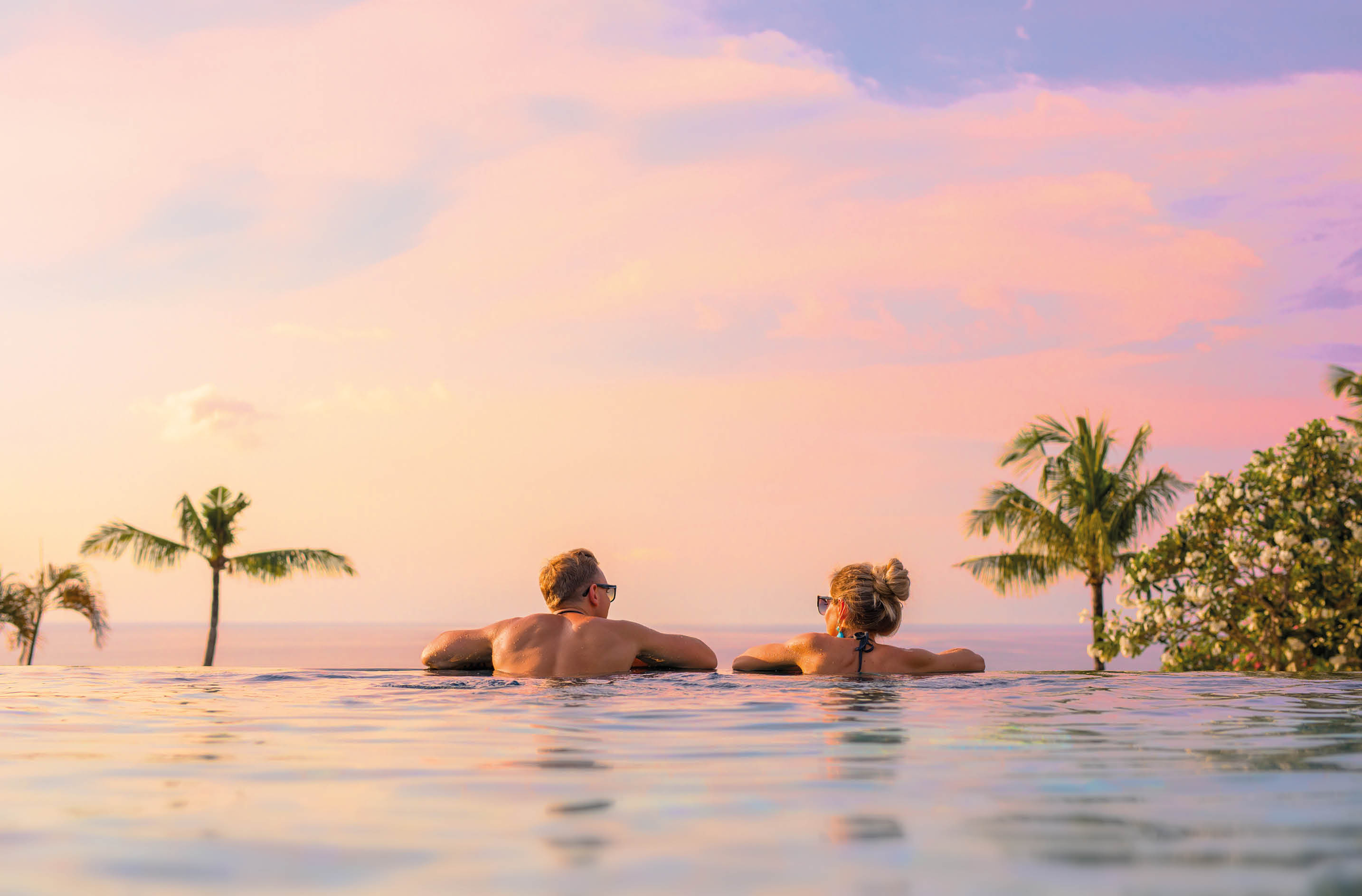 Romantic couple looking at beautiful sunset in luxury infinity pool