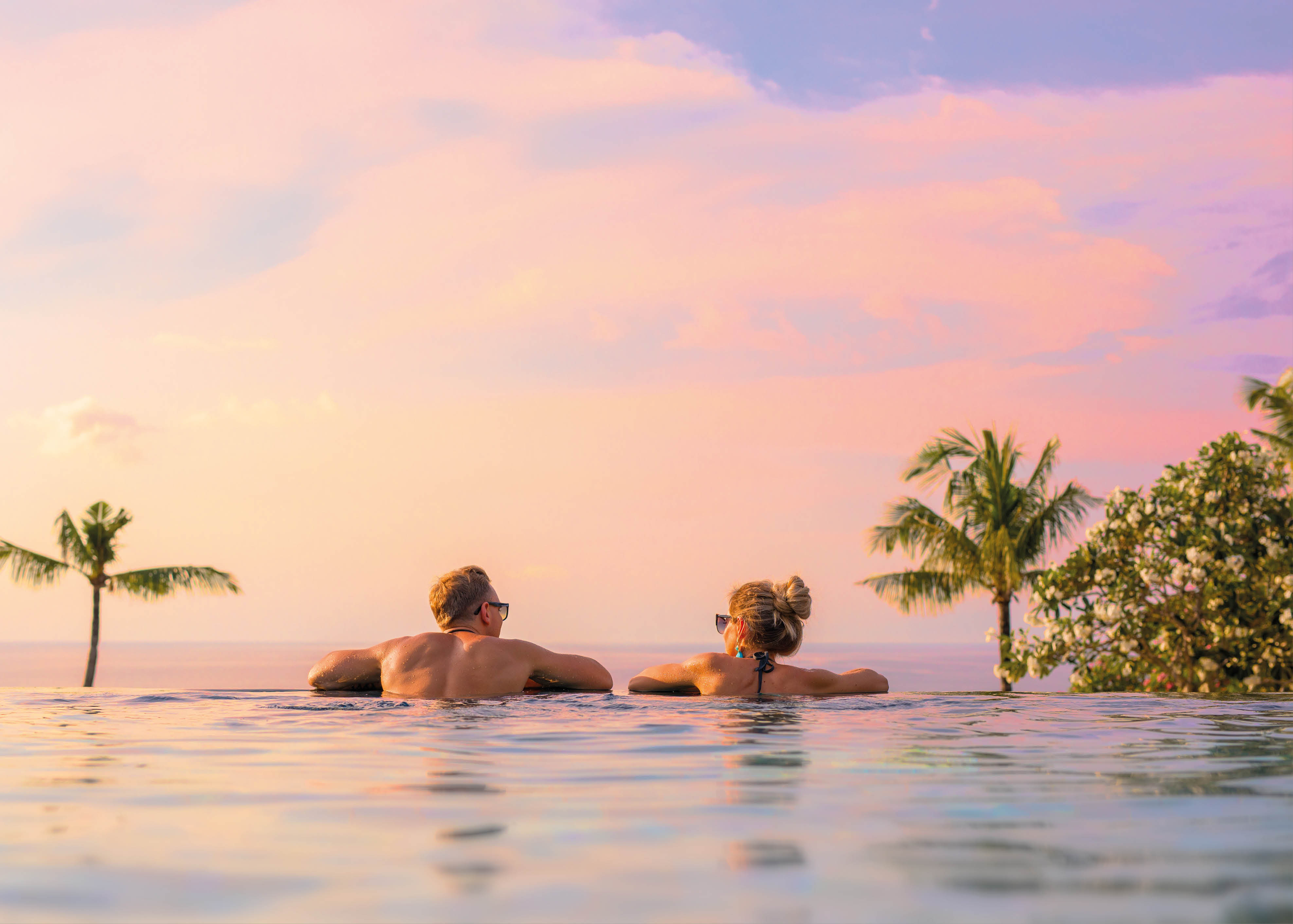 Romantic couple looking at beautiful sunset in luxury infinity pool