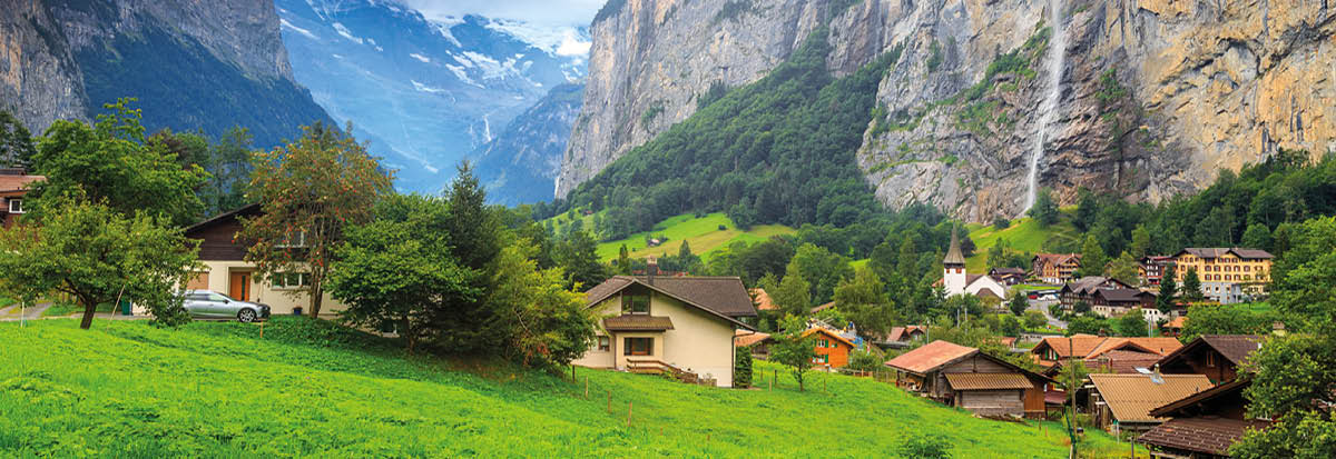 Green fields and famous touristic town with high waterfall in background,Lauterbrunnen,Bernese Oberland,Switzerland,Europe