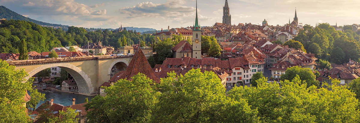 View of the city of Bern on a summer evening  On the left is the Nydeggbrücke (bridge), and the towers belong to the Nydeggkirche (church) and Berner Münster (Cathedral of Bern) 