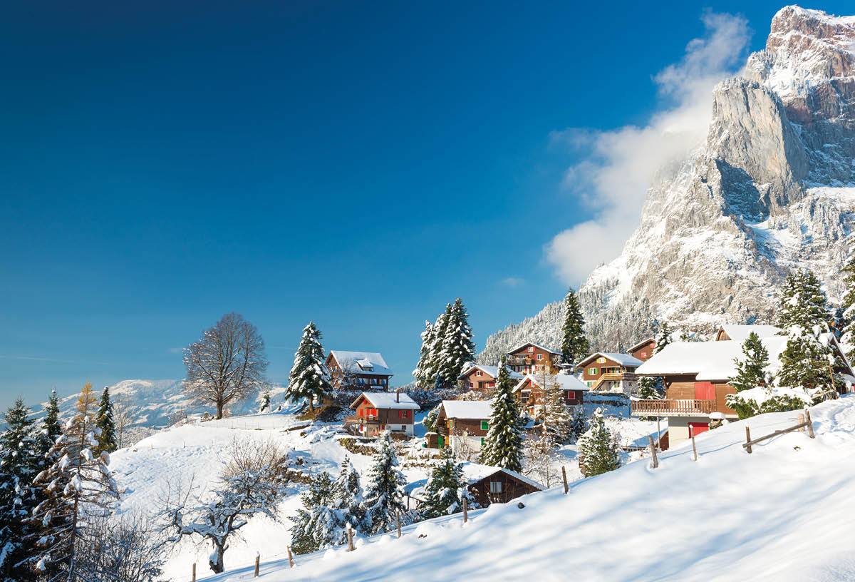 Travel to Switzerland in the winter  Alpine Village in the snow  Traditional houses with red shutters and roofs 