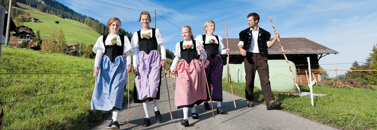 Swiss farmer family in traditional clothing walking down mountain in Lenk im Simmental, Bernese Oberland Switzerland, Lenklypse 2012