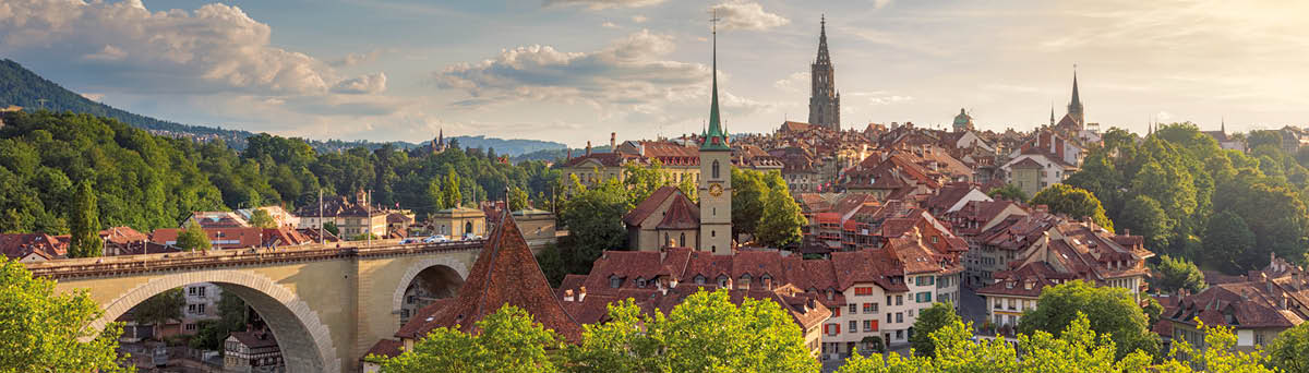View of the city of Bern on a summer evening  On the left is the Nydeggbrücke (bridge), and the towers belong to the Nydeggkirche (church) and Berner Münster (Cathedral of Bern) 