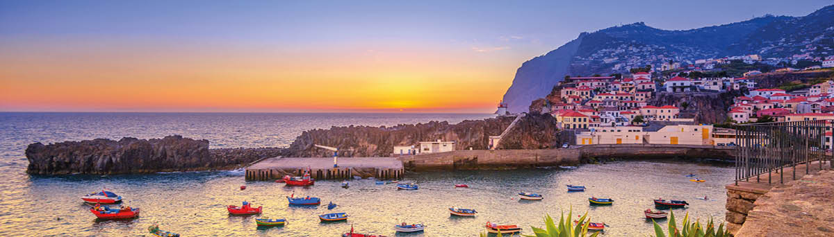 The beautiful fishing village of Camara de Lobos on the portugese Island of Madeira at sunset; in the back the landmark Cabo Girao, the world second highest steep cliff (580 m) 