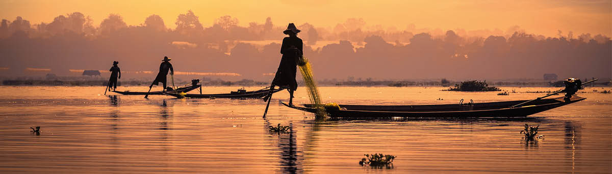Myanmar travel attraction landmark - traditional Burmese fishermen sihouettes at Inle lake on sunset, Myanmar famous for their distinctive one legged rowing style
