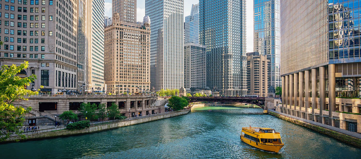Downtown Chicago Skyscraper Cityscape along the Chicago River. Typical yellow Tourboat cruising on the Chicago River towards the Michigan Lake. Chicago, Illinois, USA.