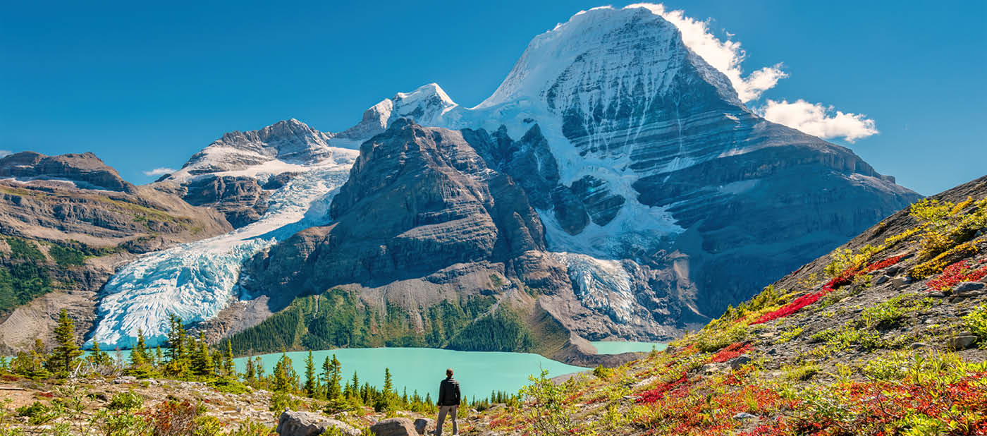 Hiker admires view of Mount Robson from above Berg Lake, Mount Robson Provincial Park, British Columbia, Canadian Rockies on a sunny afternoon.