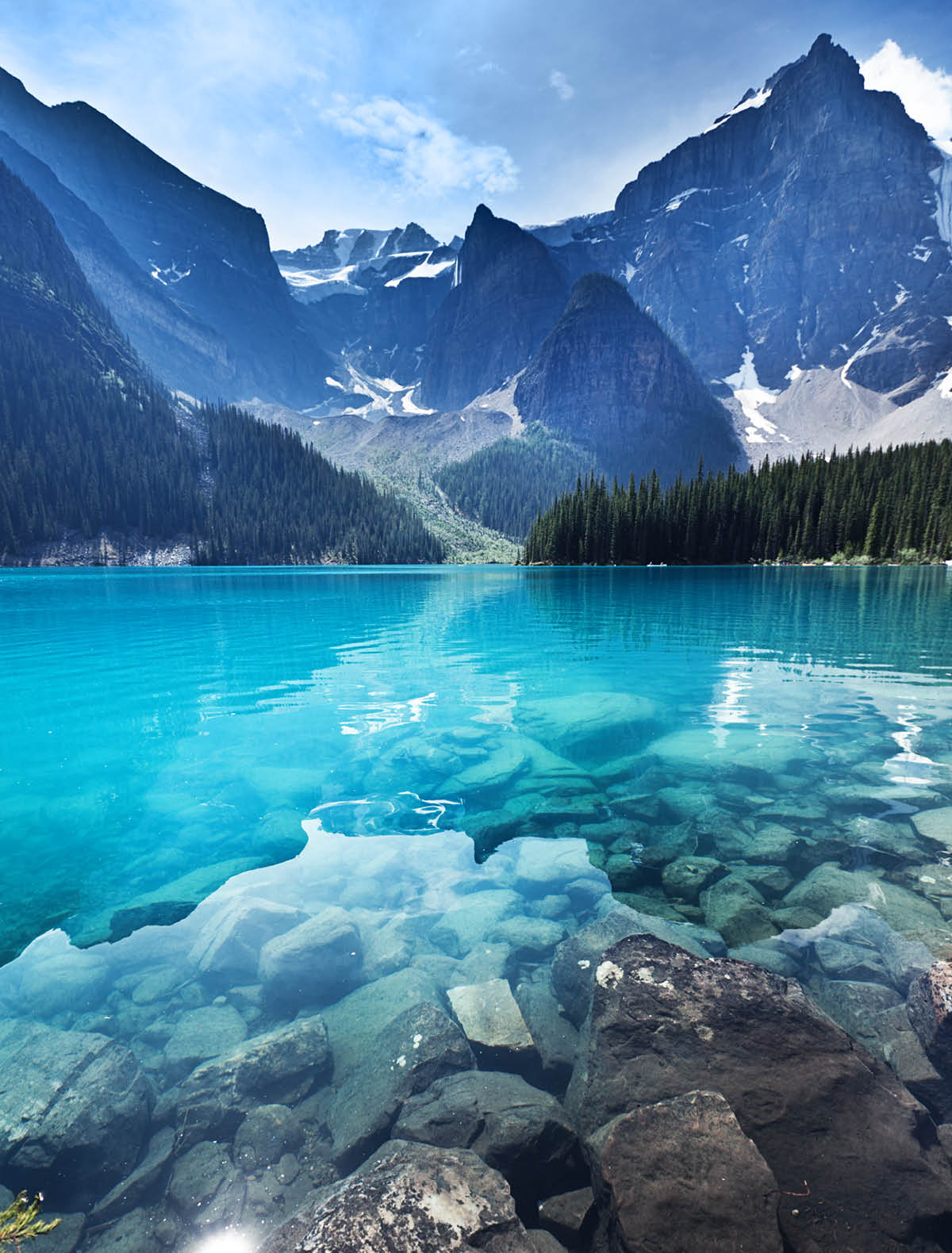Lake Moraine in the Banff National Park, Alberta, Canada, features clear emerald water and snow-capped peaks of the Canadian Rockies mountain range. The scenic landscape is a famous place and a favorite tourist travel destination for North American great outdoors nature vacations. Vertical format with copy space and no people.