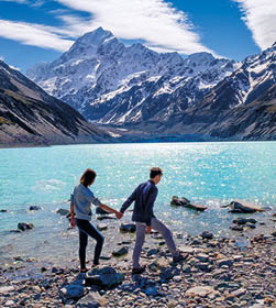 Couple enjoys beautiful scenery in New Zealand  Romantic couple holding hands  A pair of couple goes on honeymoon in natural landscape  Happiness image of a young couple exploring mount cook 